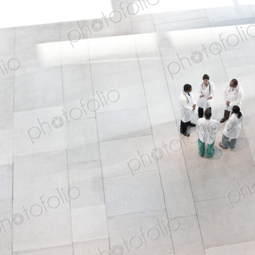 Mixed race group of doctors meeting in lobby of large hospital