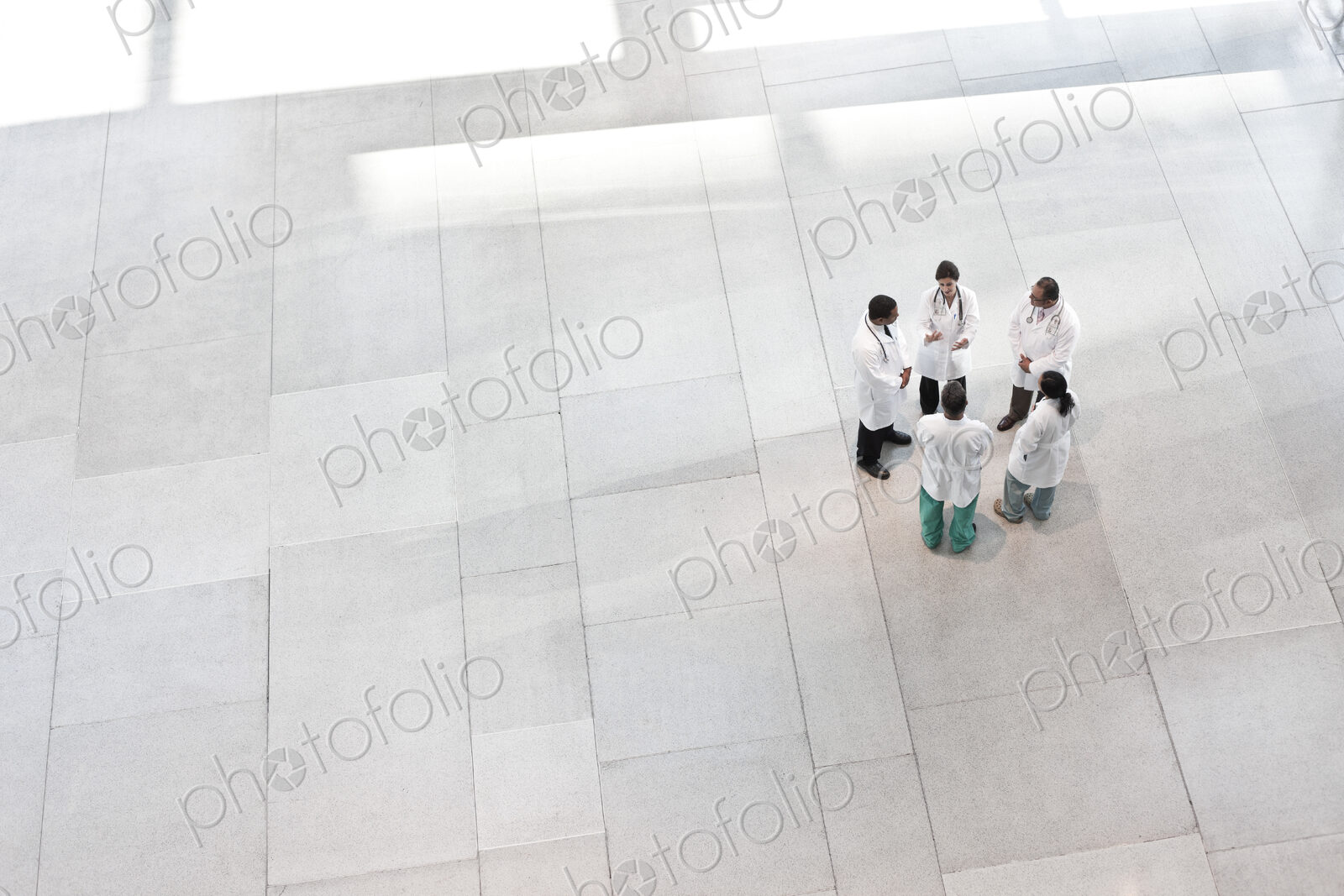 Mixed race group of doctors meeting in lobby of large hospital