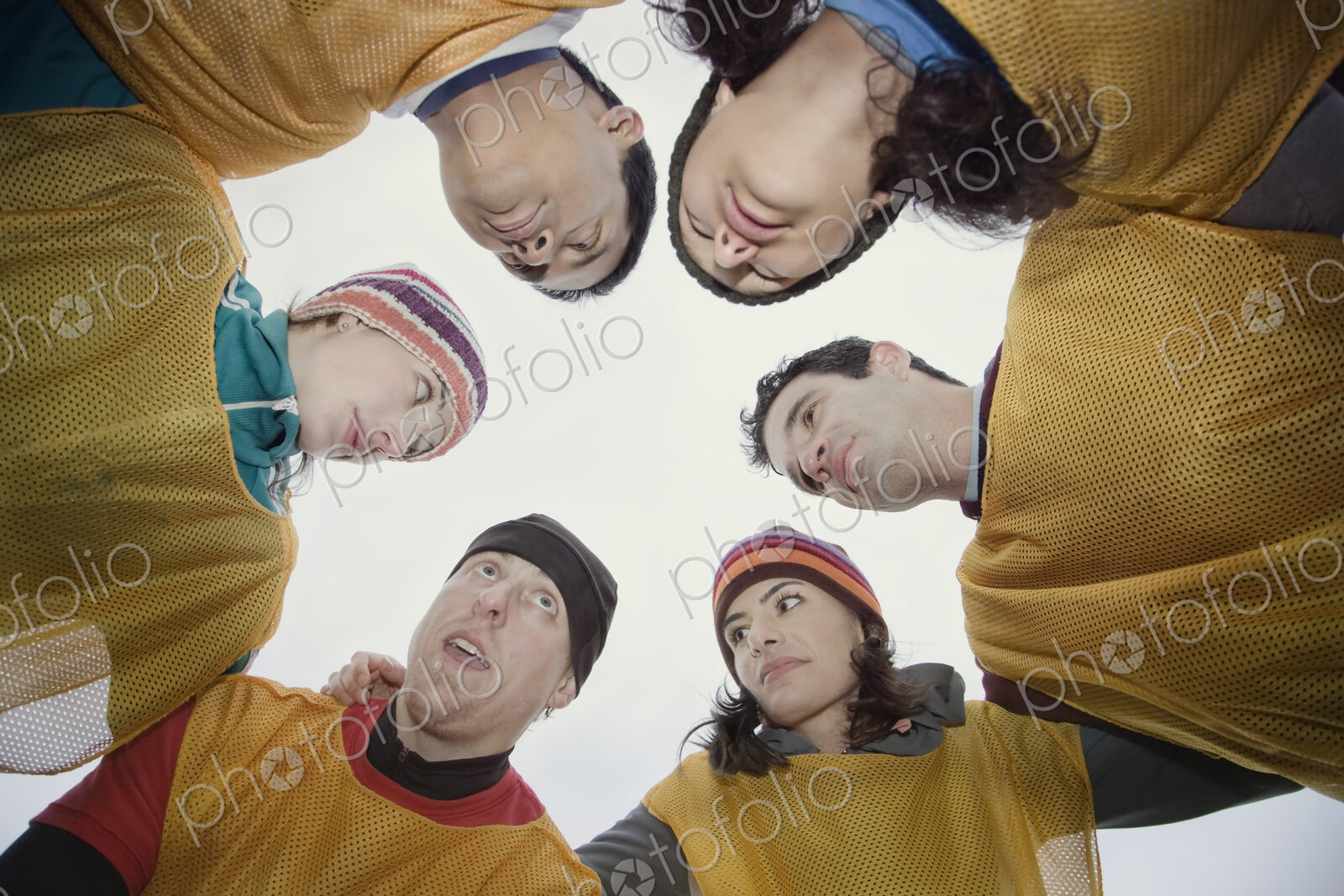 Mixed race group of men and women in a hudddle for an outdoor sporting event.