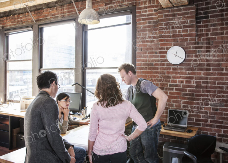 Mixed race group of people meeting to brainstorm an issue in a creative office.