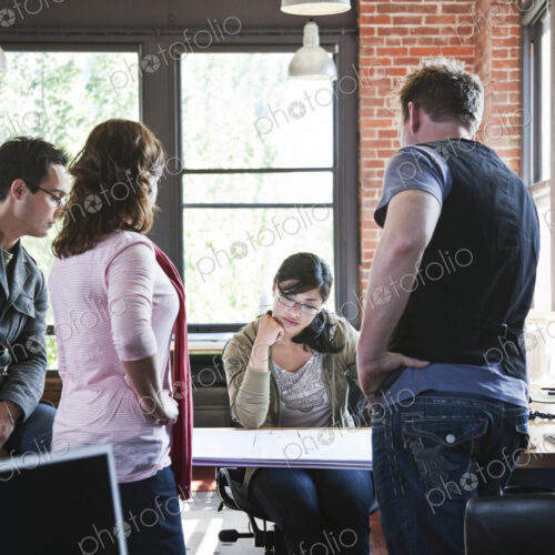 Mixed race group of people meeting to brainstorm an issue in a creative office.