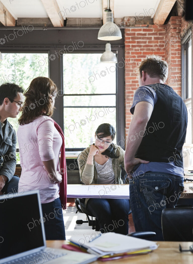 Mixed race group of people meeting to brainstorm an issue in a creative office.