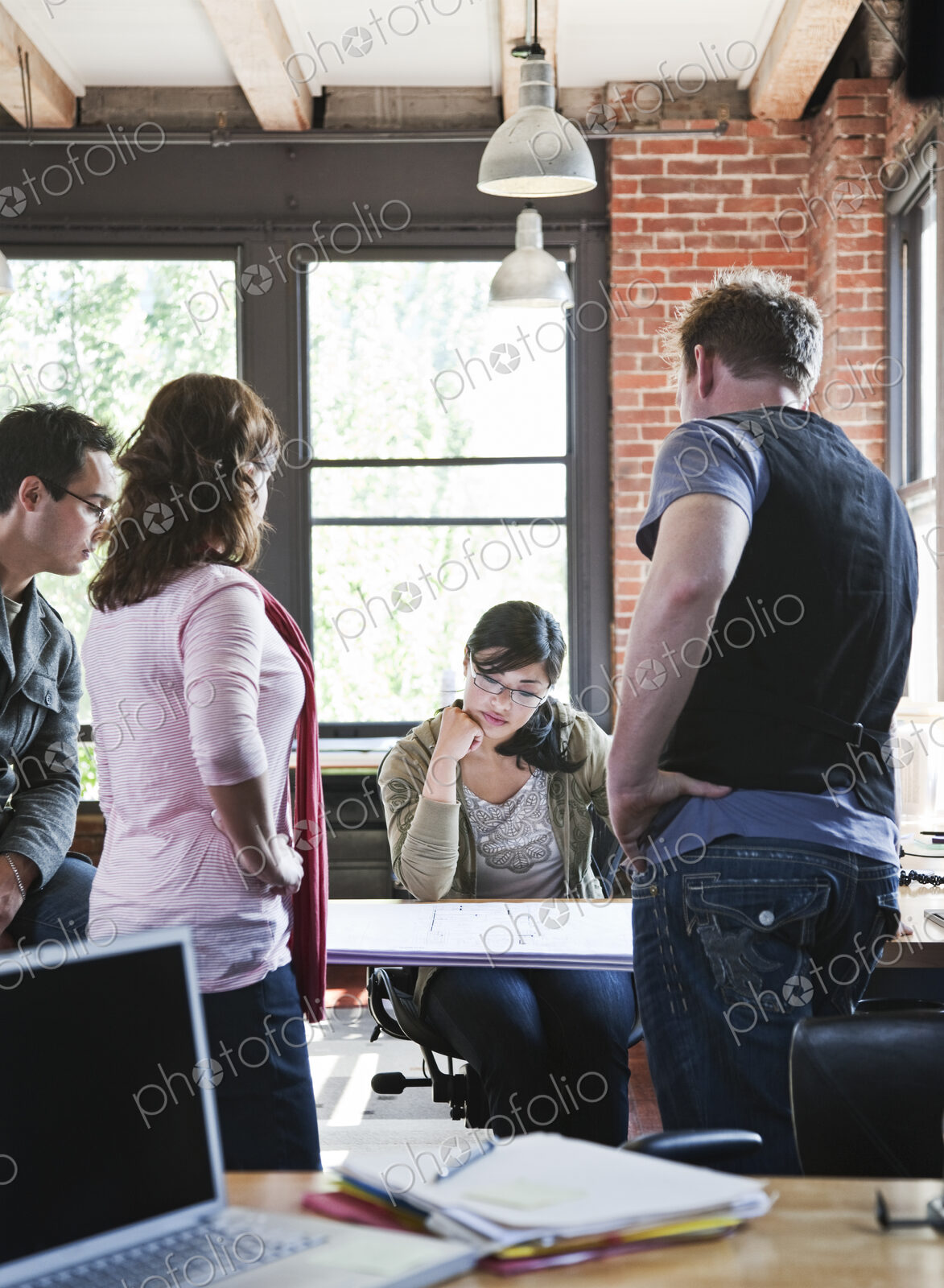 Mixed race group of people meeting to brainstorm an issue in a creative office.