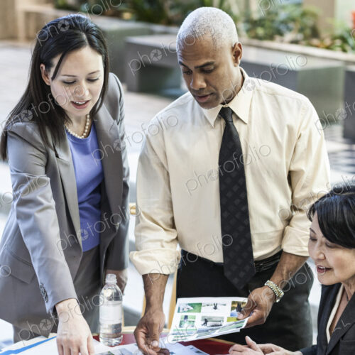 Mixed race group of three people in an informal meeting around a table in a lobby area.