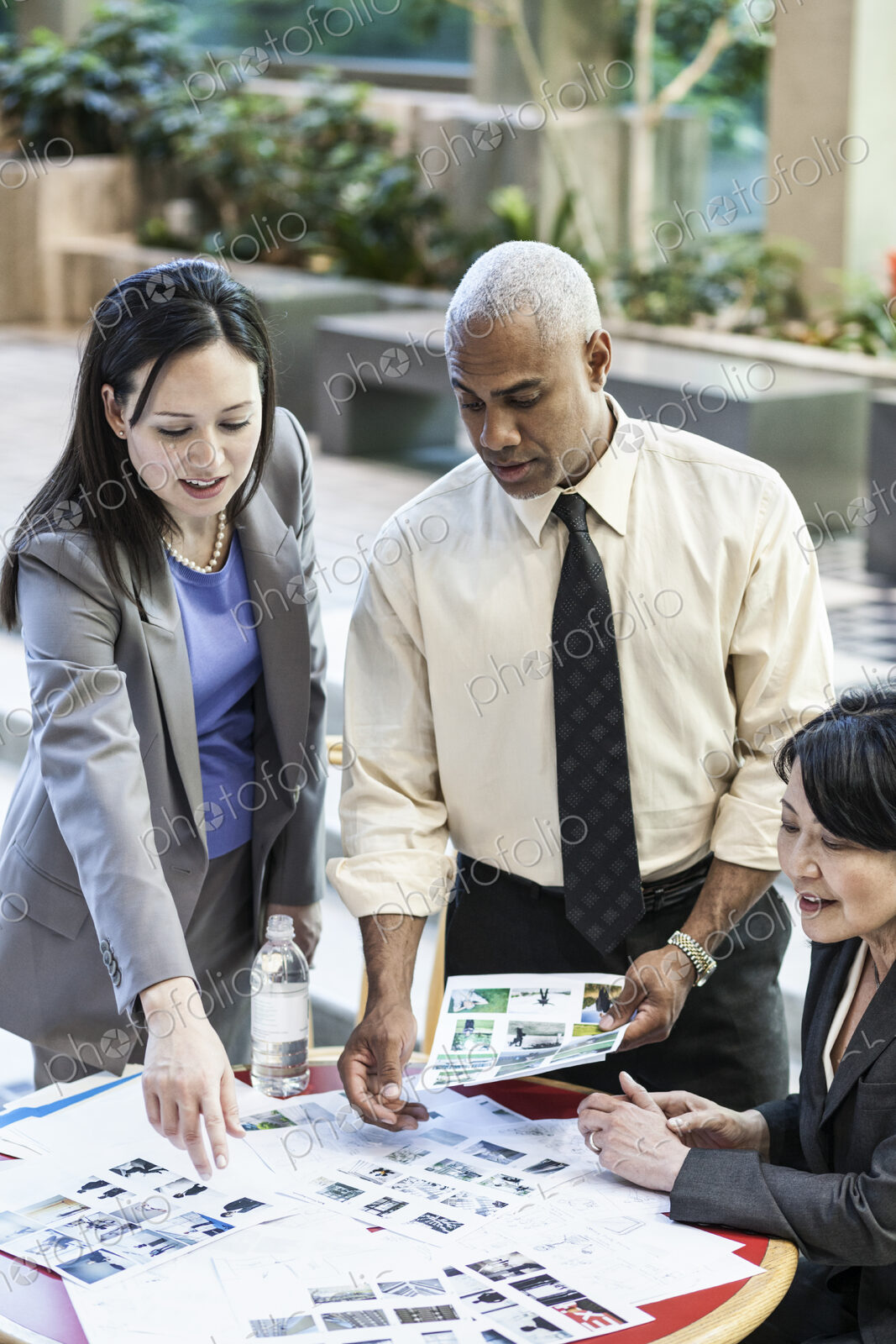 Mixed race group of three people in an informal meeting around a table in a lobby area.