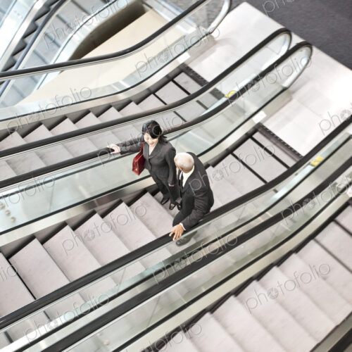 Mixed race pair of business people on the way to a meeting near a set of escalators. Mixed race pair of business people on the way to a meeting near a set of escalators.