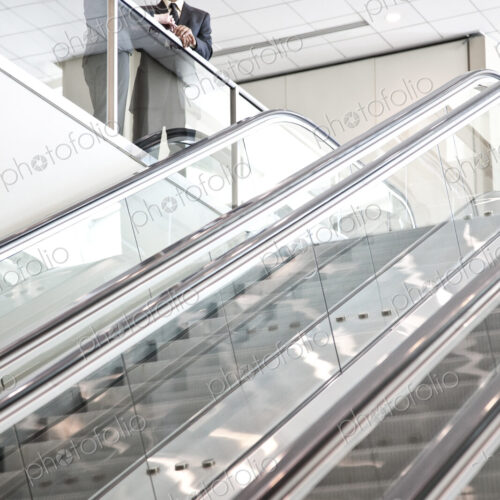 Mixed race pair of business people on the way to a meeting near a set of escalators. Mixed race pair of business people on the way to a meeting near a set of escalators.