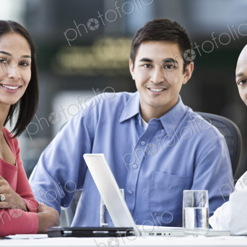 Mixed race team of business people at a table in a business center. Mixed race team of business people at a table in a business center.