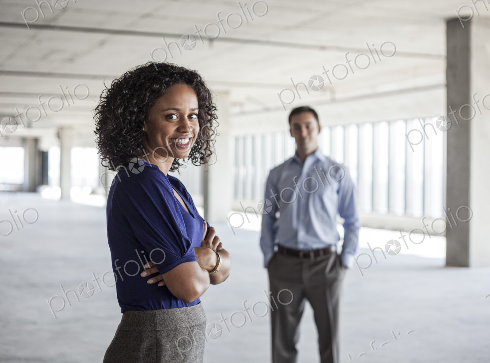 Mixed race team of business people in a large empty raw office space.