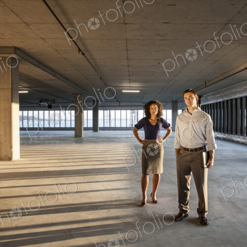 Mixed race team of business people in a large empty raw office space.