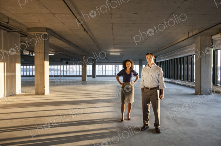 Mixed race team of business people in a large empty raw office space.