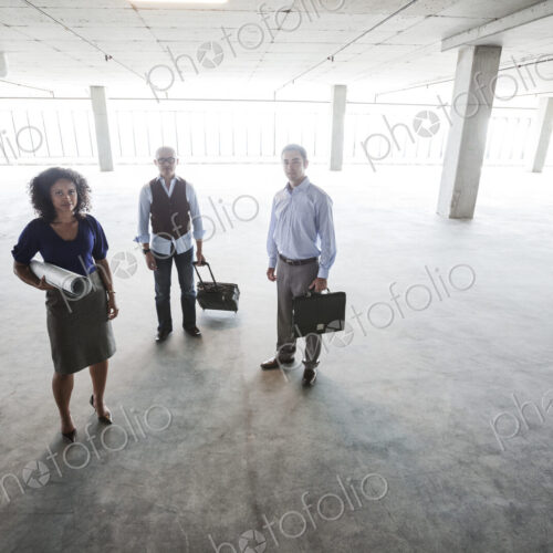 Mixed race team of business people in their new large empty raw office space.