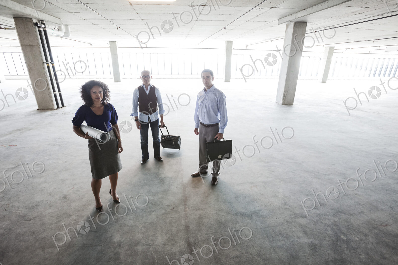 Mixed race team of business people in their new large empty raw office space.