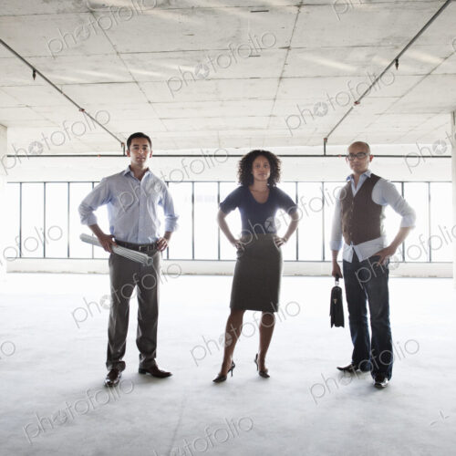 Mixed race team of business people in their new large empty raw office space.
