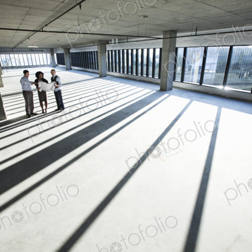 Mixed race team of business people touring a new empty raw office space.
