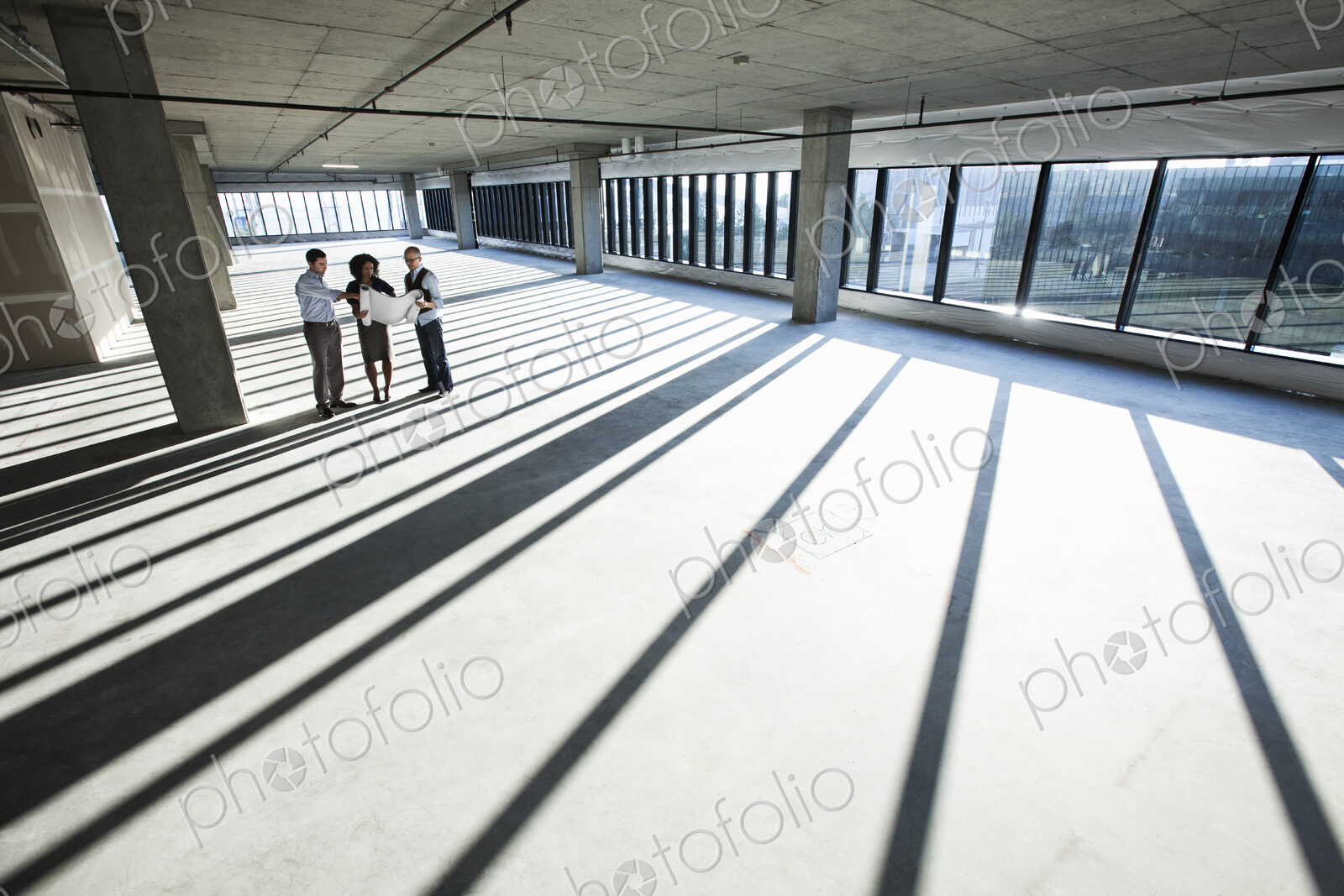 Mixed race team of business people touring a new empty raw office space.