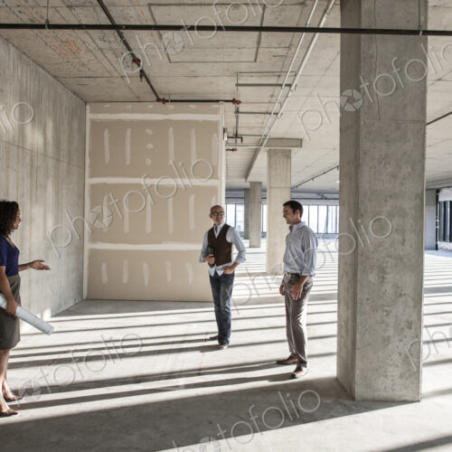 Mixed race team of business people touring a new empty raw office space.