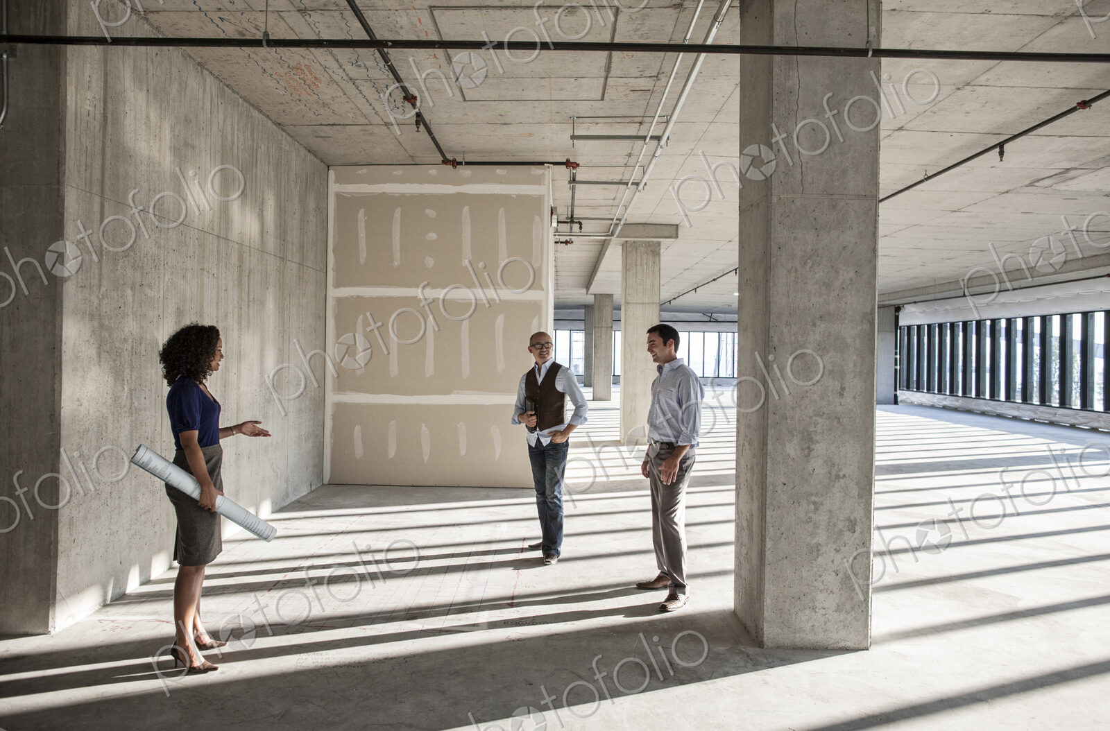 Mixed race team of business people touring a new empty raw office space.