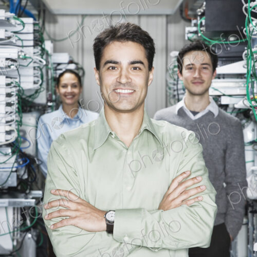 Mixed race team of technicians working on computer servers in a computer server farm. Mixed race team of technicians working on computer servers in a computer server farm.