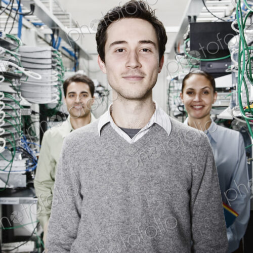 Mixed race team of technicians working on computer servers in a computer server farm. Mixed race team of technicians working on computer servers in a computer server farm.