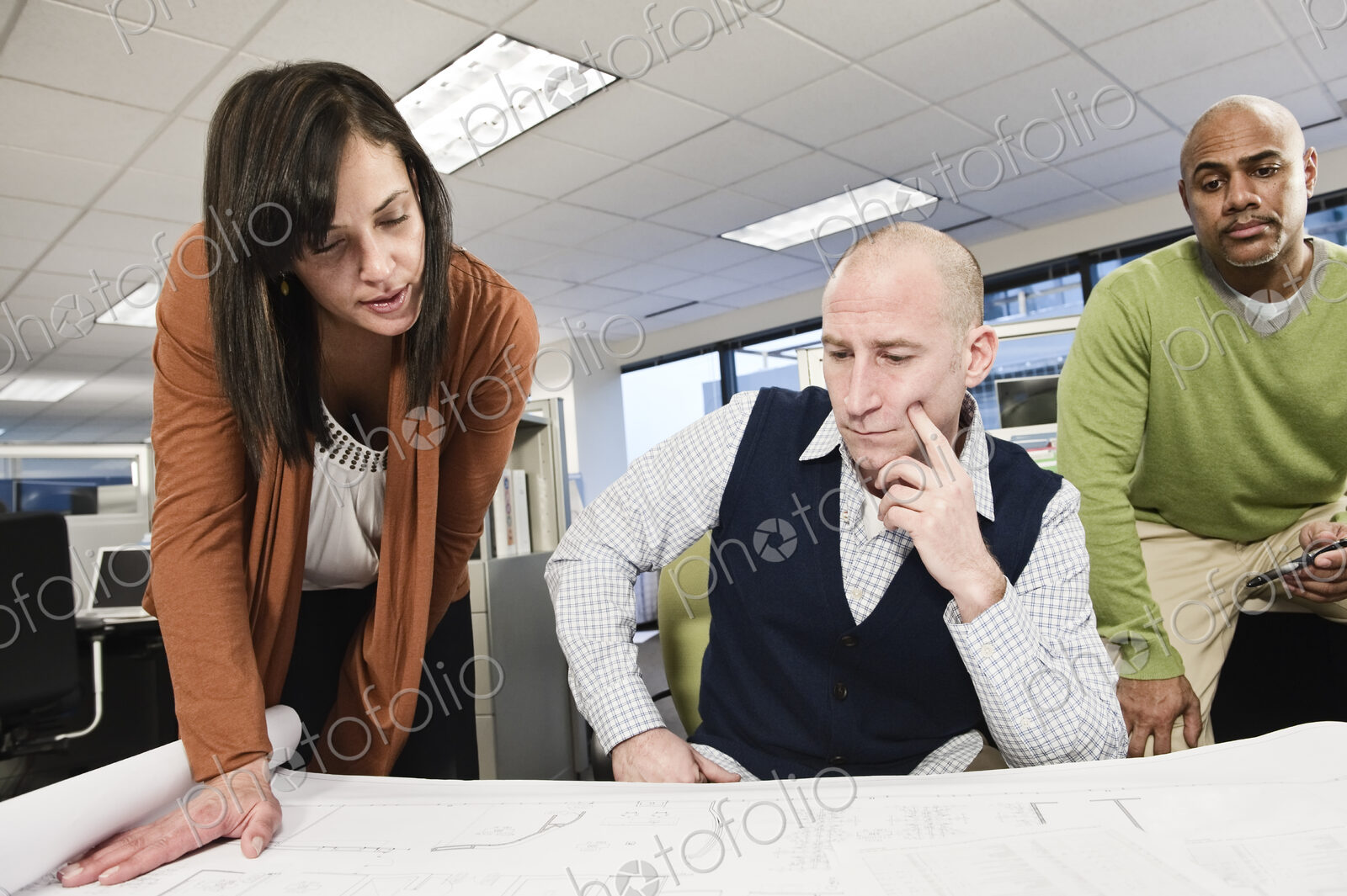 Mixed race team of three people working on a project in a cubicle office.
