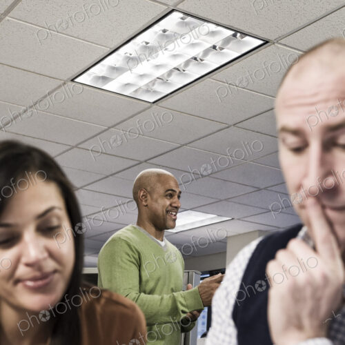 Mixed race team of three people working on a project in an office cubicle area. Mixed race team of three people working on a project in an office cubicle area.
