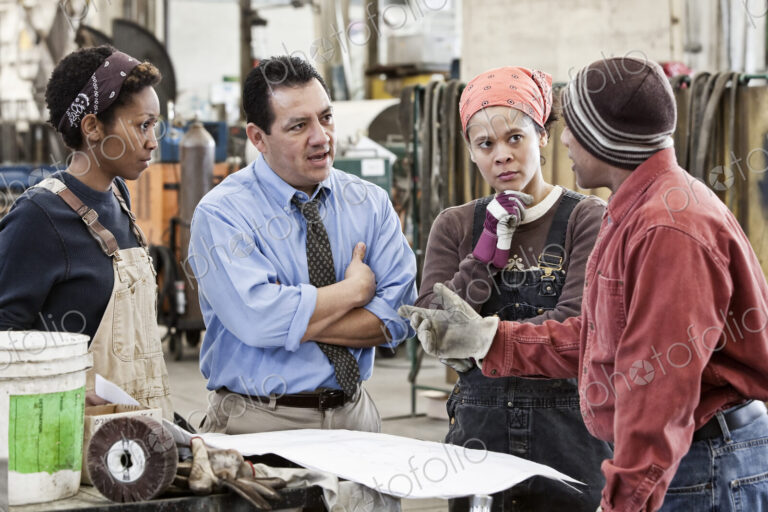 Mixed race team of workers and hispanic man manager talking over an issue in a sheet…