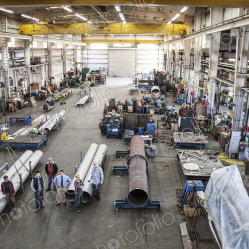 Mixed race team of workers and management people in a large sheet metal factory