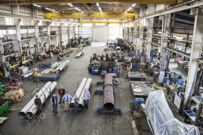 Mixed race team of workers and management people in a large sheet metal factory