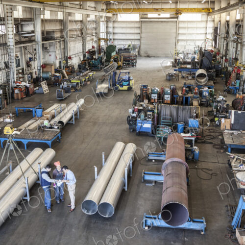 Mixed race team of workers and management people in a large sheet metal factory