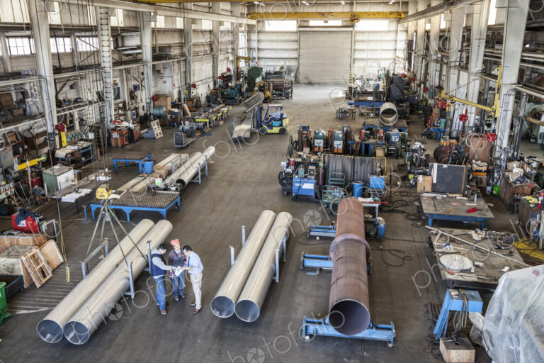 Mixed race team of workers and management people in a large sheet metal factory