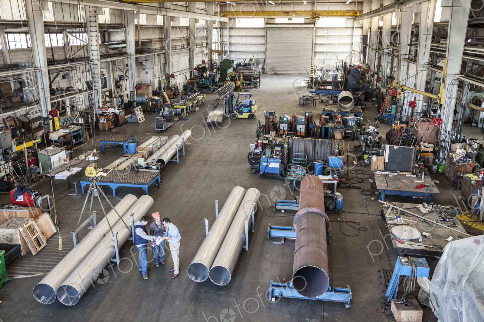 Mixed race team of workers and management people in a large sheet metal factory