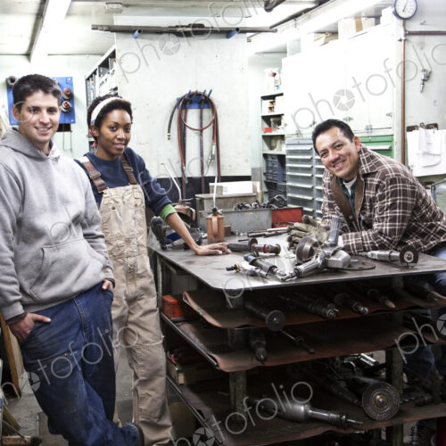 Mixed race team of workers and management people in a large sheet metal factory