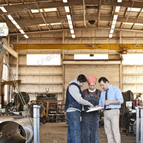 Mixed race team of workers and management people in a large sheet metal factory Mixed race team of workers and management people in a large sheet metal factory