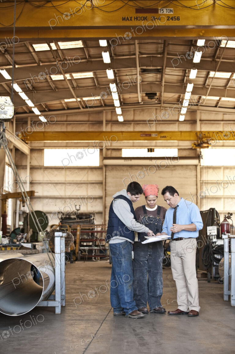 Mixed race team of workers and management people in a large sheet metal factory