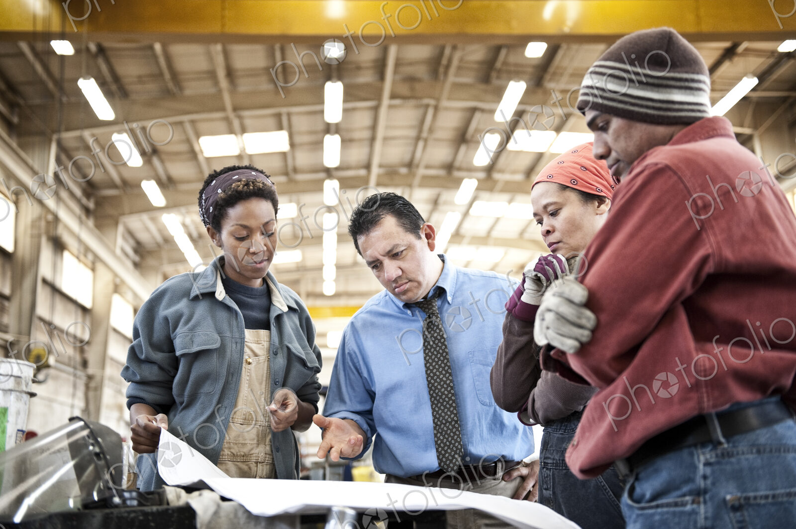 Mixed race team of workers and management people in a large sheet metal factory