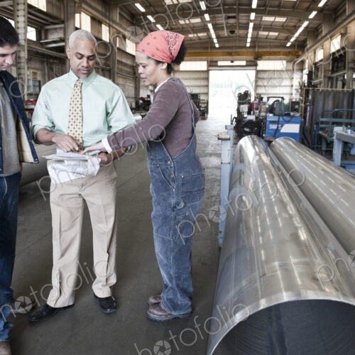 Mixed race team of workers and management people in a large sheet metal factory