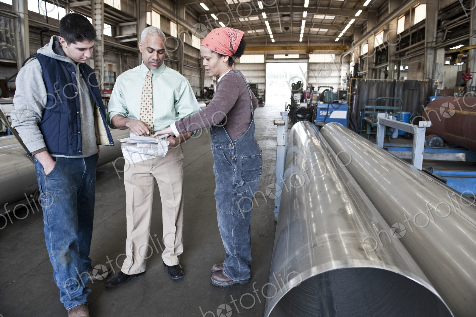 Mixed race team of workers and management people in a large sheet metal factory