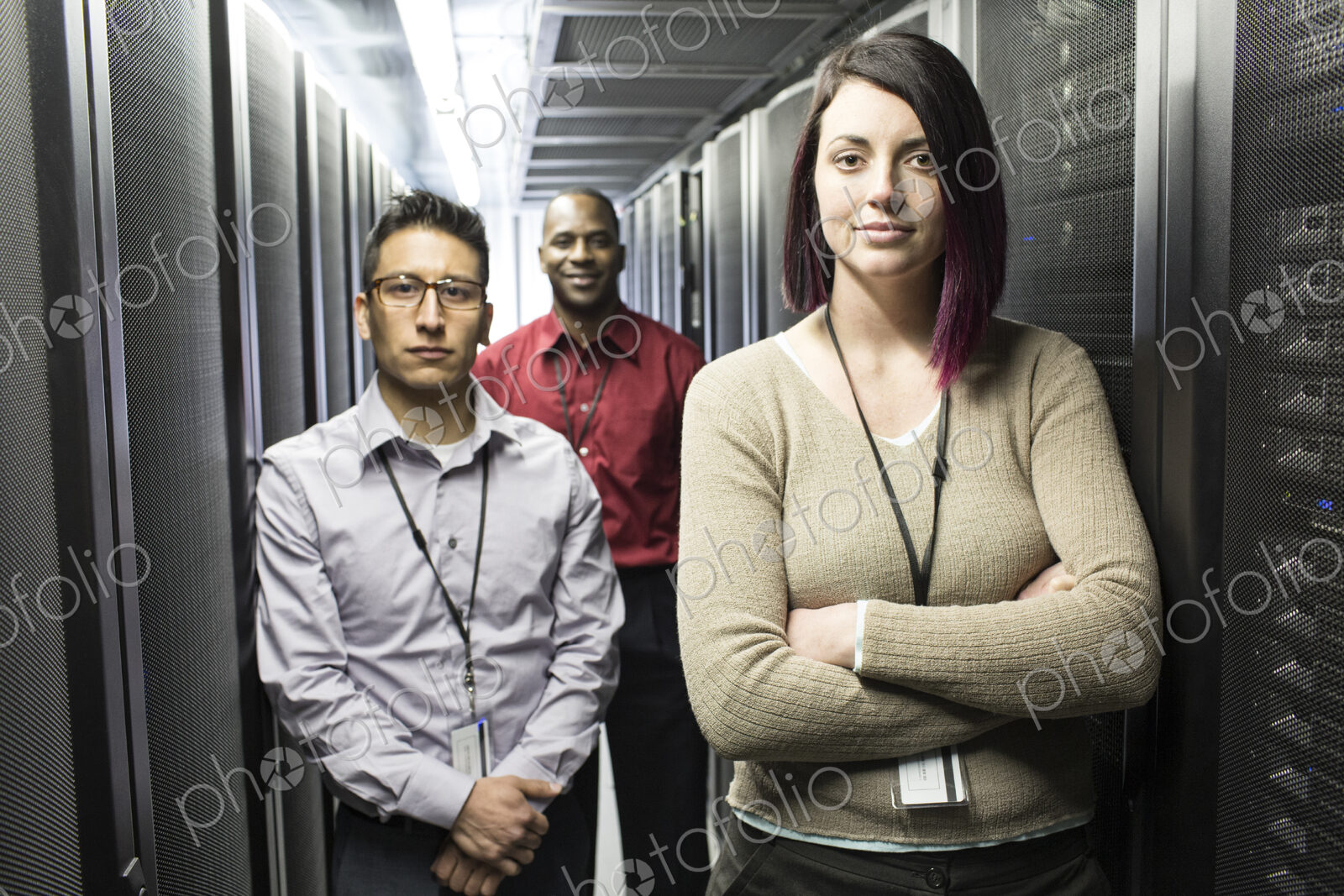 Mixed race technical team in an aisle of a large computer server farm.