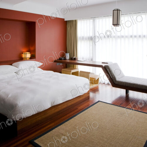 Modern bedroom, with double bed and wall recess and chaise longue by window
