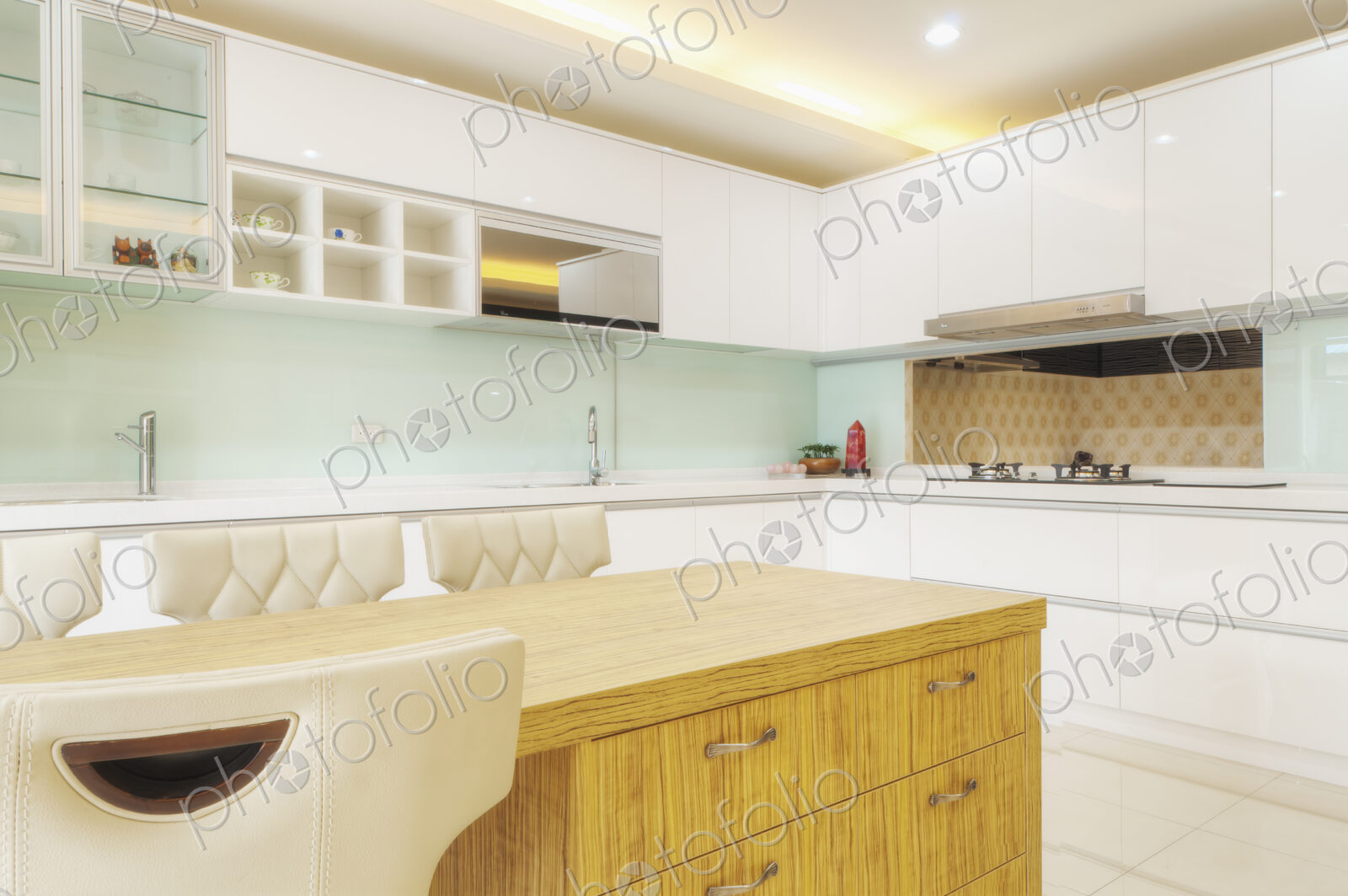 Modern kitchen interior with two sinks, gas stove, fitted cupboards and appliances.