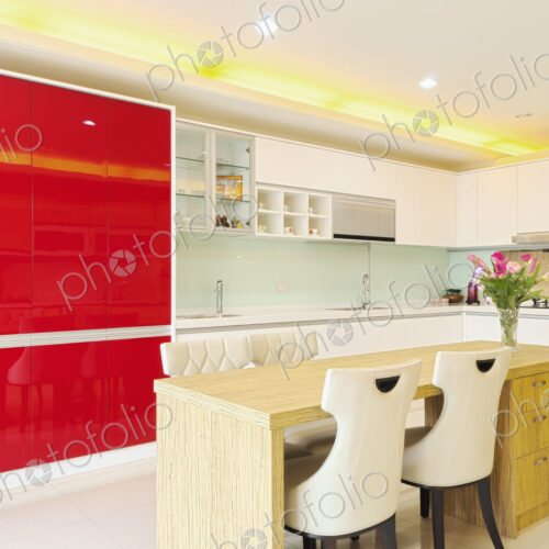 Modern kitchen with red cabinets, two sinks, gas stove, fitted cupboards with red…