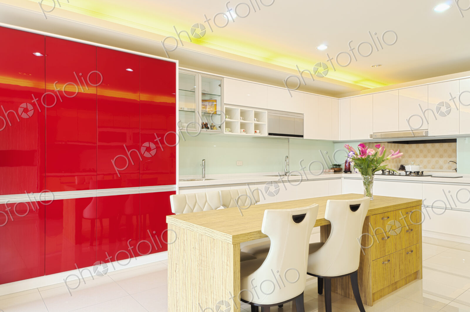 Modern kitchen with red cabinets, two sinks, gas stove, fitted cupboards with red…