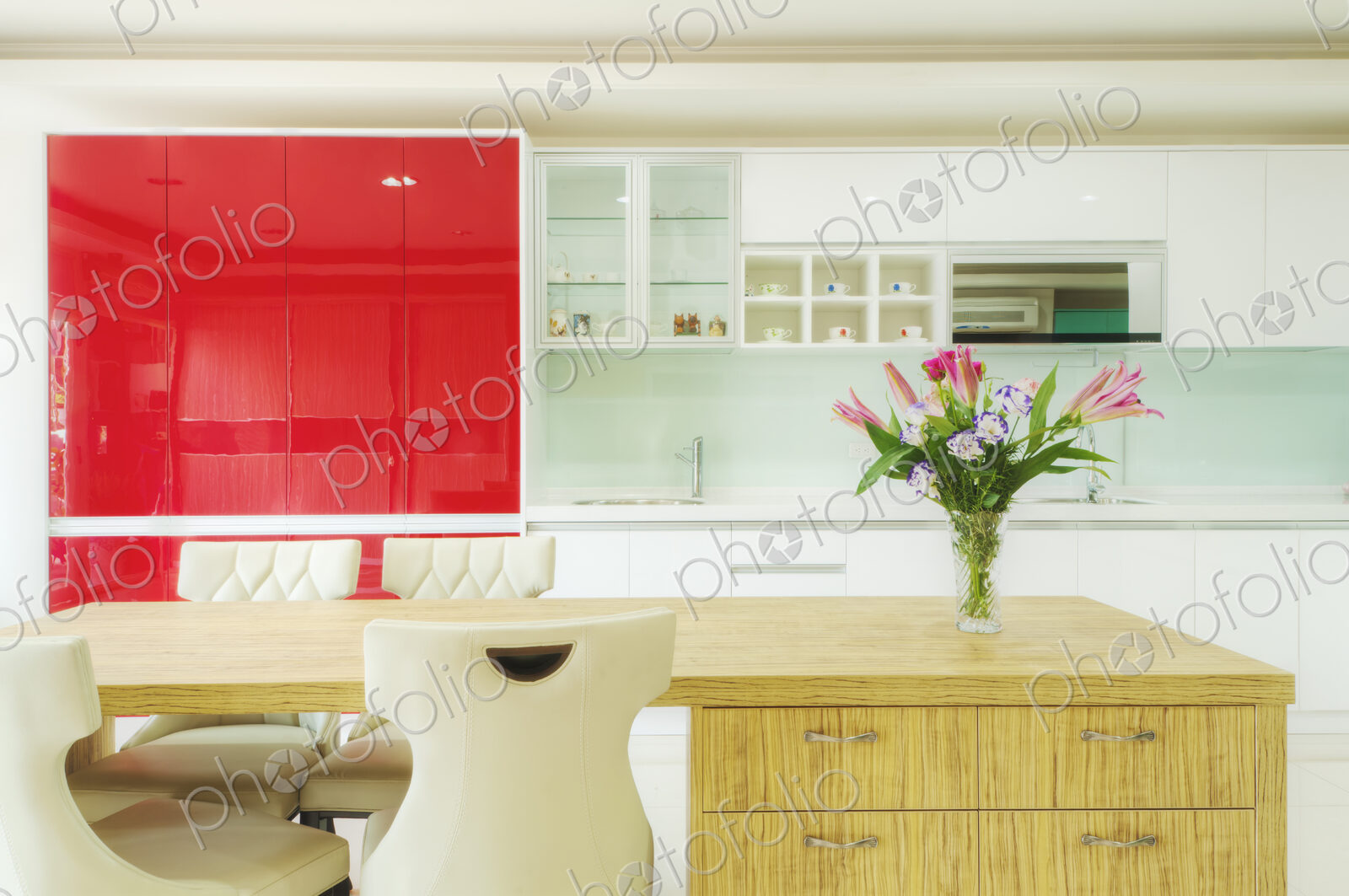 Modern kitchen with red cabinets, two sinks, gas stove, fitted cupboards with red…