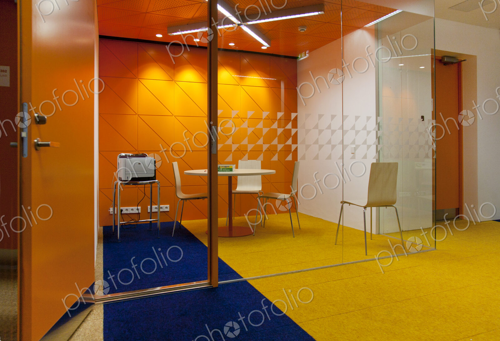 Modern meeting area in an office, a clear glass wall and chairs and table.