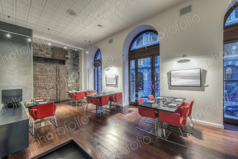 Modern restaurant interior with red chairs.
