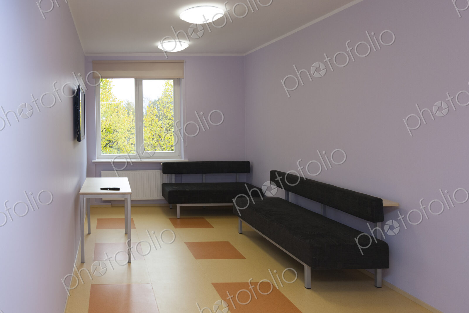 Modern youth hostel building. Black couches in a television room.