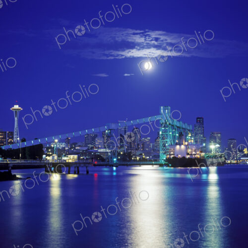 Moon over illuminated Seattle city skyline at night, Washington, United States Moon over illuminated Seattle city skyline at night, Washington, United States