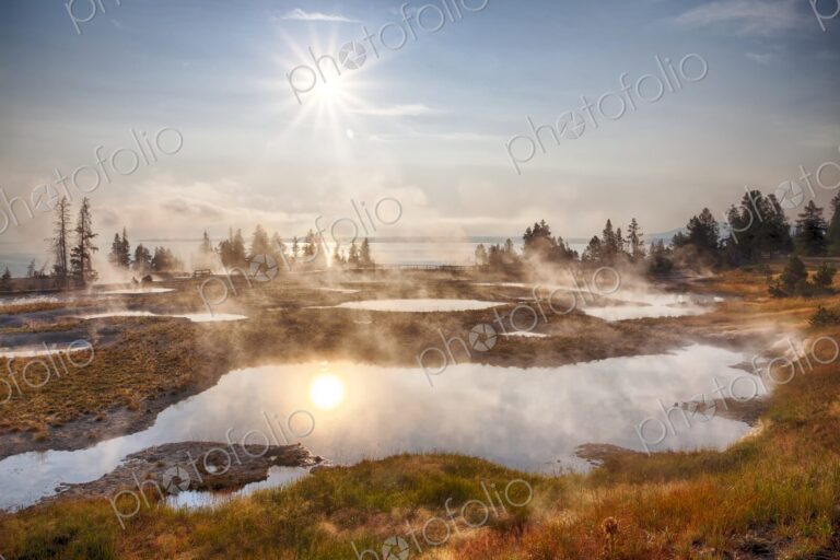 Morning sun glows over steaming geyser pools in Yellowstone's West Thumb Geyser Basin,…