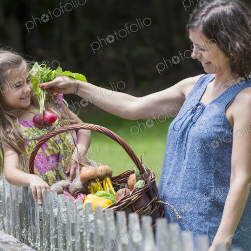 Mother and daughter standing in a garden with a basket of vegetables. Mother and daughter standing in a garden with a basket of vegetables.